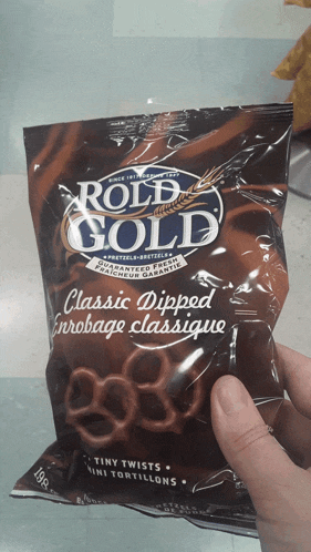 a person is holding a bag of roll gold classic dipped pretzels