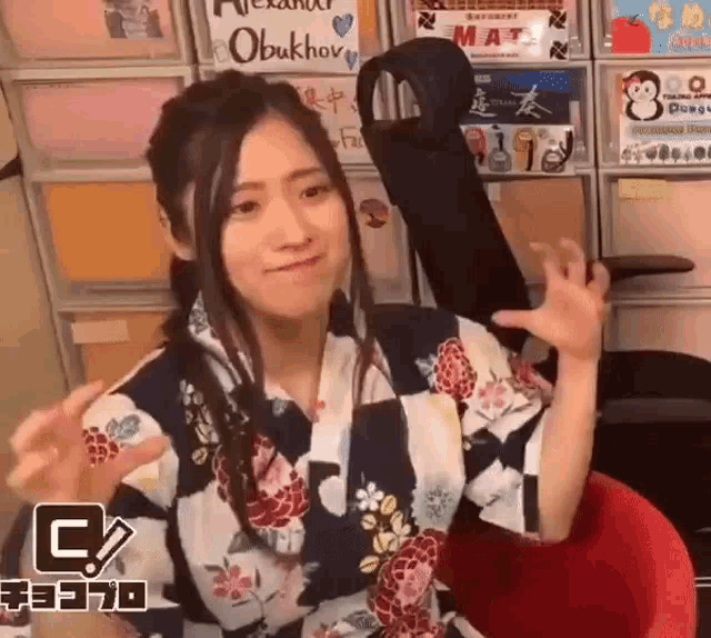 a woman in a kimono is sitting in a red chair holding a guitar .
