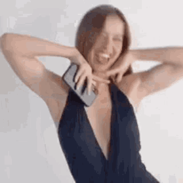 a woman in a black dress is taking a selfie with her cell phone .