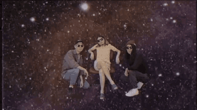 three people are posing for a picture in front of a galaxy .
