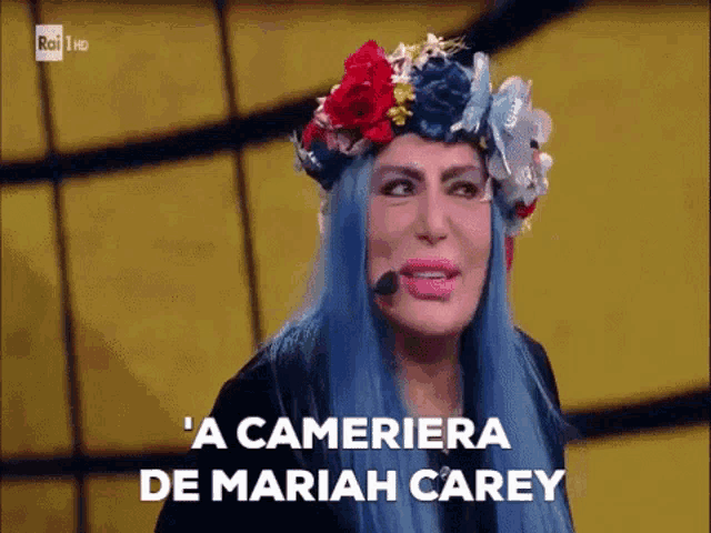 a woman with blue hair has a flower crown on her head and says ' a cameriera de mariah carey '
