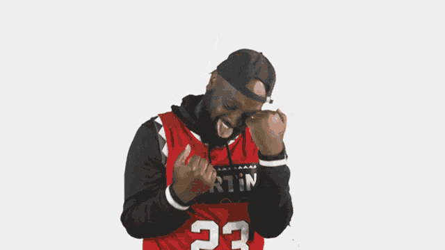 a man wearing a red jersey with the number 23 on it is sticking his tongue out