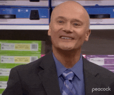 a man in a suit and tie is smiling in front of a peacock logo
