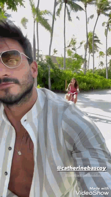 a man wearing sunglasses and a striped shirt is standing next to a woman in a bikini