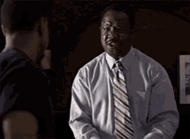 a man in a suit and tie is shaking hands with another man in a black shirt .