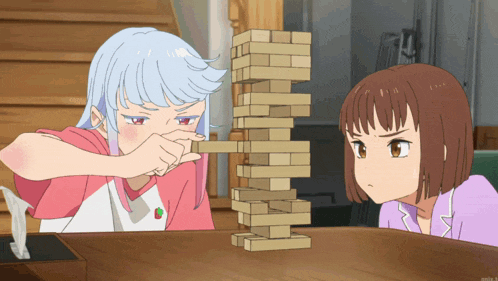 two girls are playing a game of jenga with a strawberry shirt on