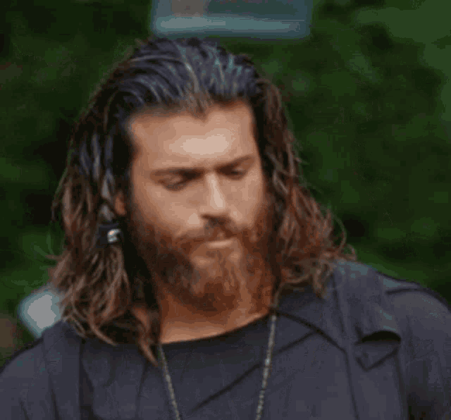 a man with long hair and a beard is standing next to a woman and looking at her .