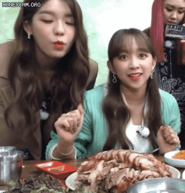 two girls are sitting at a table with a plate of food in front of them