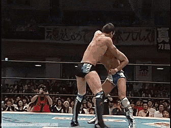 two men are wrestling in a ring in front of a crowd and a sign that says ' a ' on it