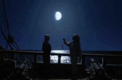 two people standing on a deck looking at a full moon