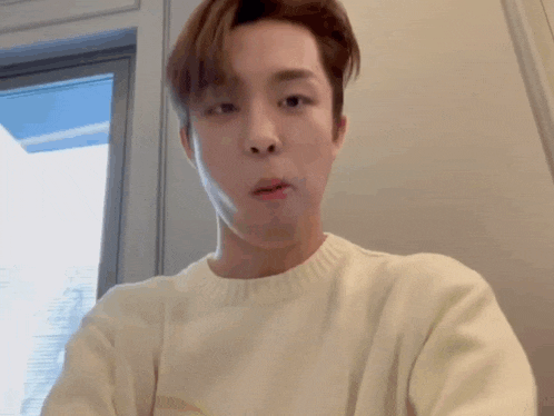 a man in a white sweater is making a funny face .