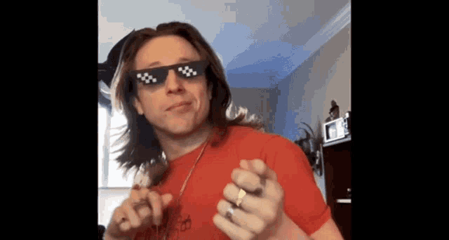 a man wearing a red shirt and sunglasses is making a face