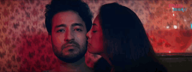 a woman kisses a man on the cheek in front of a sign that says ' pinks music '