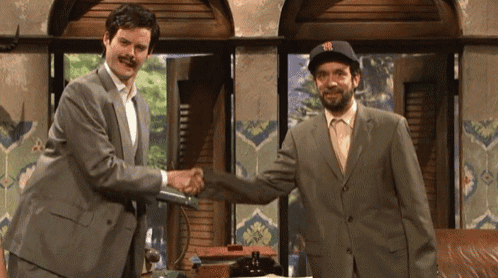 a man in a ny hat shakes hands with a man in a suit