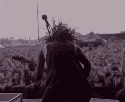 a man is playing a guitar on a stage in front of a crowd at a concert .