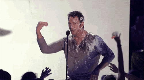 a man is covered in slime while standing in front of a microphone in front of a crowd .