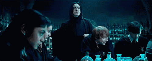 a group of people are sitting around a table in a dark room with bottles of liquid .