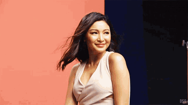 a woman in a white dress stands in front of a pink and blue wall