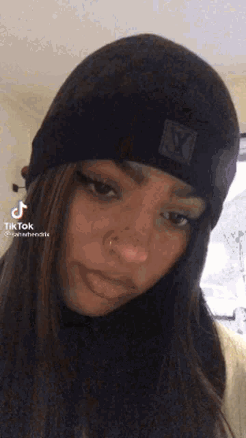 a woman wearing a black beanie and a nose ring .