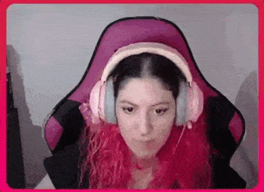 a woman with pink hair is wearing headphones while sitting in a pink chair .