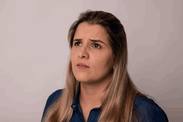 a woman wearing a denim shirt makes a silly face