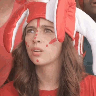 a woman wearing a red and white hat and red paint on her face