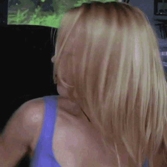 a blonde woman in a blue tank top is sitting in the back seat of a car