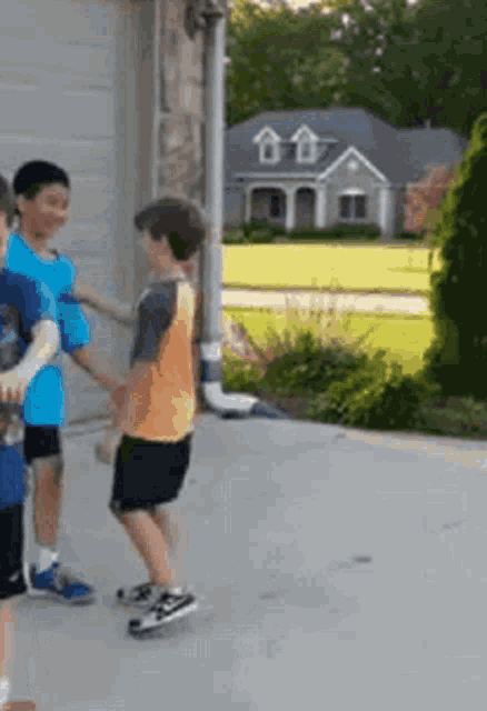 a group of young boys are standing in front of a house .