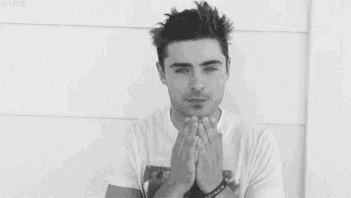 a black and white photo of a man with his eyes closed covering his mouth with his hands .