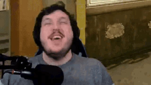 a man is laughing in front of a microphone in a room .