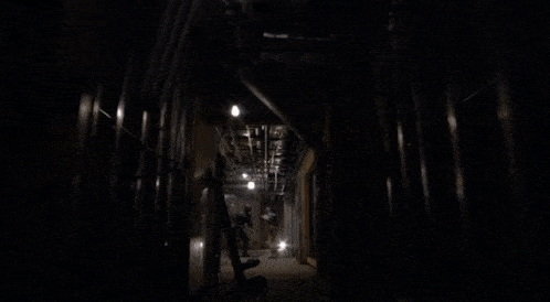 a person is walking through a dark room with a sign on the wall that says " no smoking "