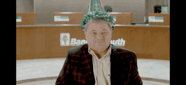 a man wearing a party hat is sitting in front of a bank south counter