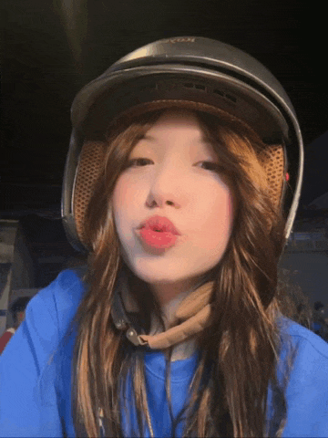 a girl wearing a helmet and a blue shirt is making a funny face