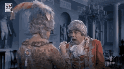 a man in a costume is talking to another man in a room with a speech bubble that says mediaset