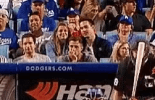 a group of people sitting in a stadium with dodgers.com written on the wall