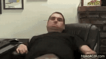 a man in a black shirt is sitting in a chair with his head on the desk .
