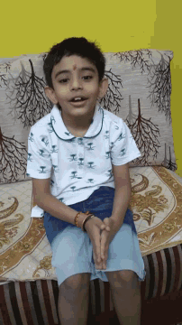 a young boy is laying on a couch with a pillow with trees on it