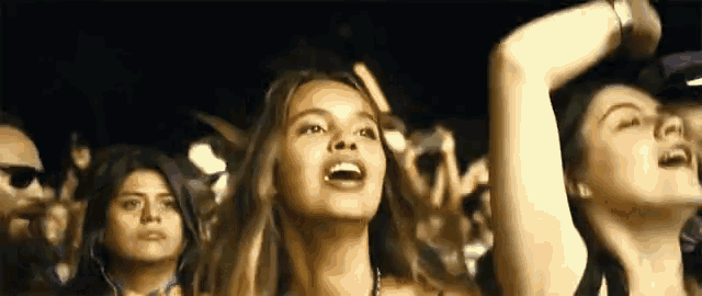 a crowd of people are watching a concert and one woman is screaming