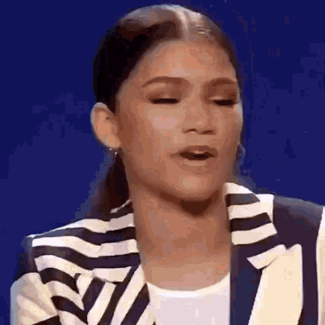 a close up of a woman wearing a striped jacket and earrings .