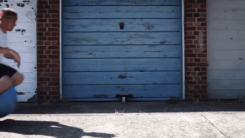 a man riding a skateboard in front of a blue garage