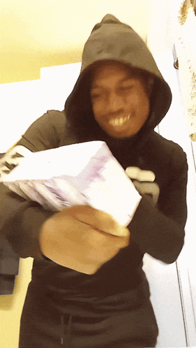 a man in a hoodie holds a stack of money in his hands