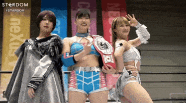three female wrestlers are posing for a photo in front of a banner that says stardom