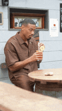 a man sits at a table holding a drink with a straw in front of a sign that says " rotary "