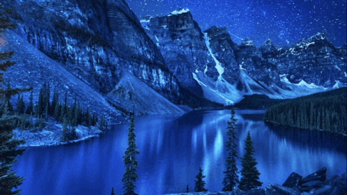 a lake surrounded by mountains at night with a starry sky