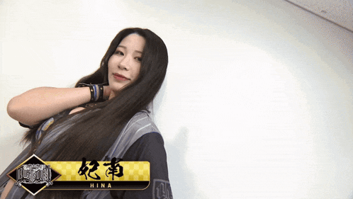 a woman with long hair is standing in front of a white wall with a banner that says hina