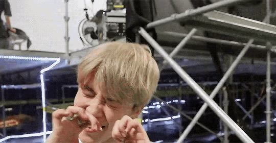 a young man with blonde hair is crying while holding a piece of paper in his hand .