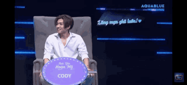 a man is sitting in a chair with a sign that says cody