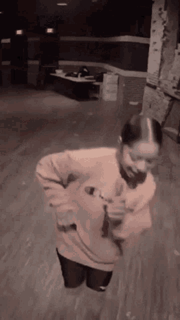 a woman in a pink sweater is dancing on a wooden floor