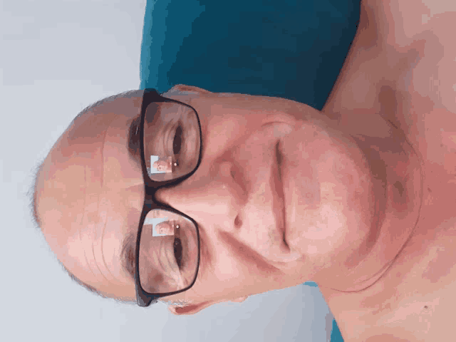 a man wearing glasses has a reflection of a person 's face