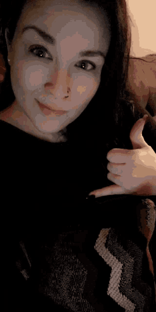 a woman with a nose ring giving a thumbs up sign